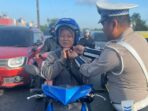 Personel Satlantas Polresta Barelang memberikan helm kepada pengendara. Foto: Istimewa