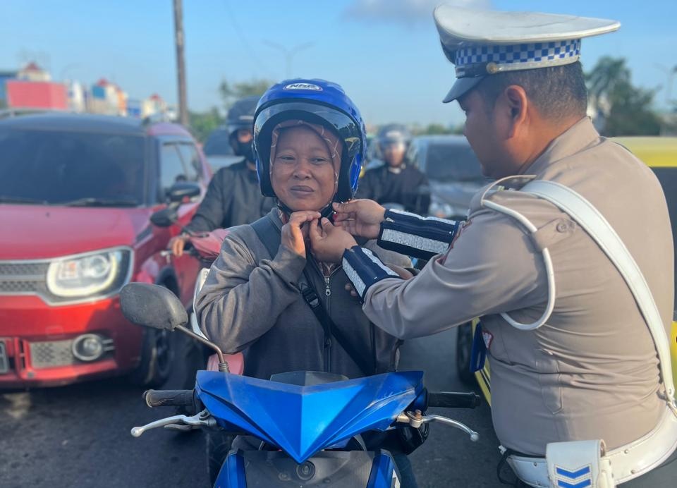 Personel Satlantas Polresta Barelang memberikan helm kepada pengendara. Foto: Istimewa