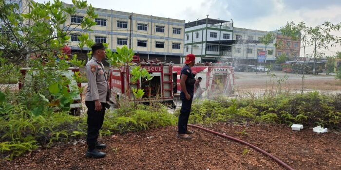 Seorang personel kepolisian tampak mengamankan proses pemadaman api yang membakar lahan kosong seluas sekitar satu hektare di Tanjungpinang. Foto: Ist